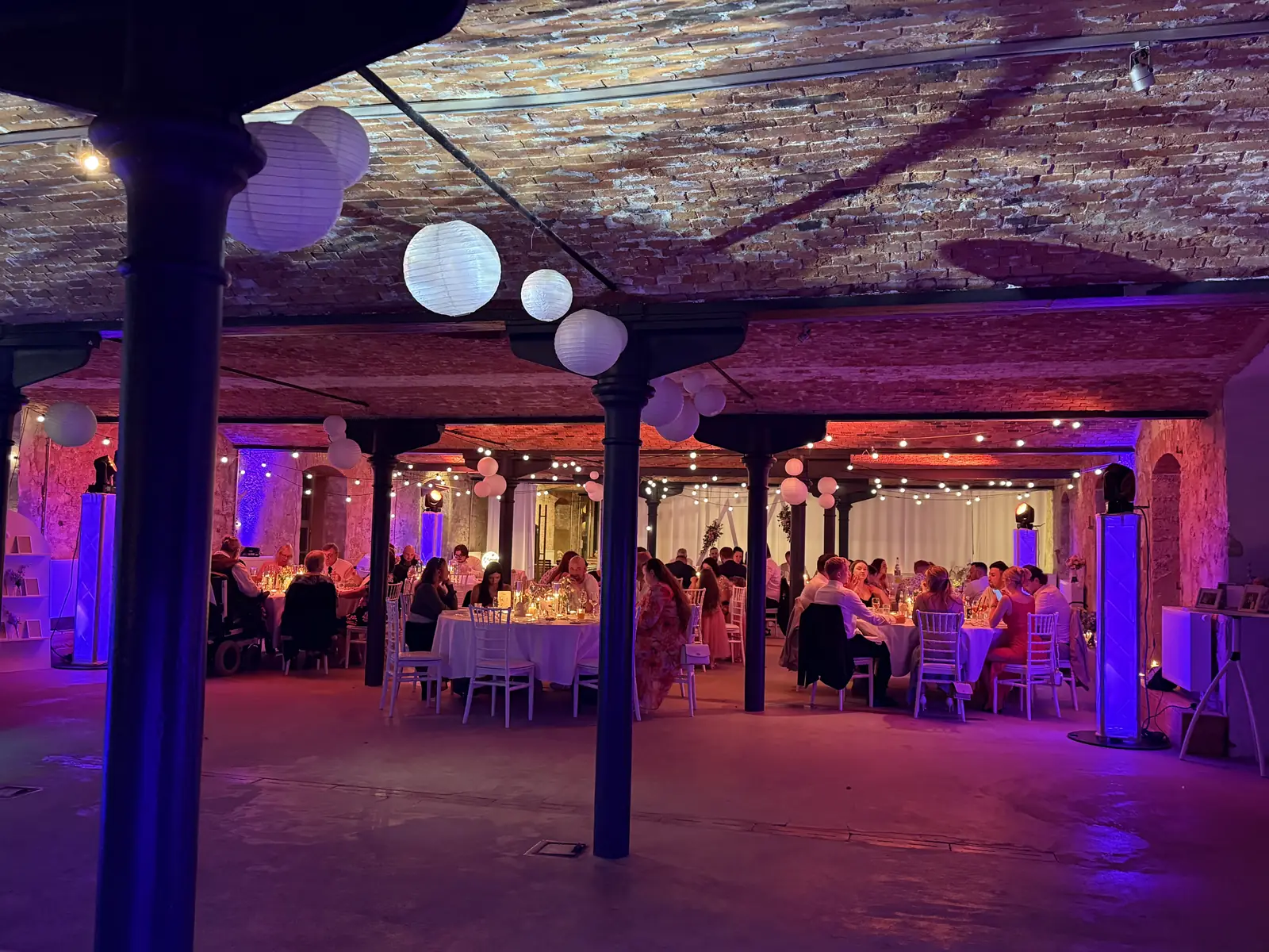 Hochzeitsgesellschaft in einer Backstein-Location mit Lichtkonzept von Weber.Events